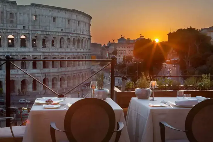 Outdoor dining at the Aroma restaurant in Rome, with a privileged view of the Colosseum at sunset.