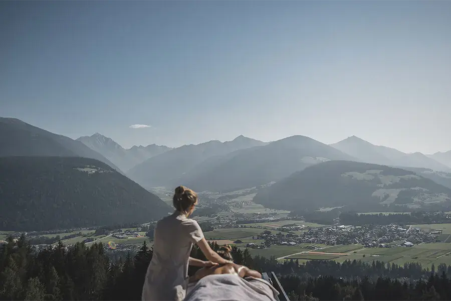 Woman receiving an outdoor massage with a panoramic view of the Dolomite Mountains in northern Italy.