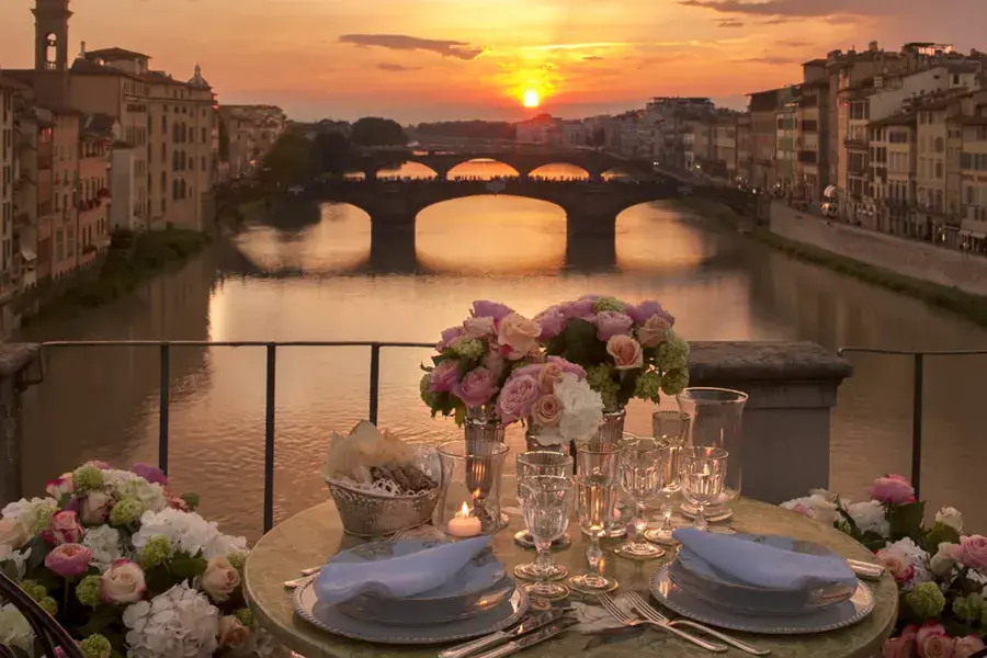 Decorated table for a romantic dinner at sunset with a view of the Ponte Vecchio and the Arno River in Florence.