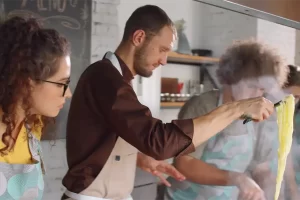 Chef demonstrating how to cook fresh pasta during a hands-on cooking class, with participants attentively observing in a cozy kitchen setting.