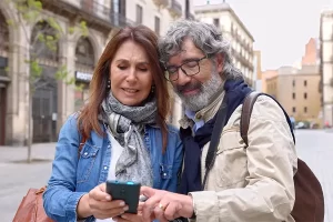 Happy couple smiling and toasting with wine glasses while enjoying a romantic moment outdoors.