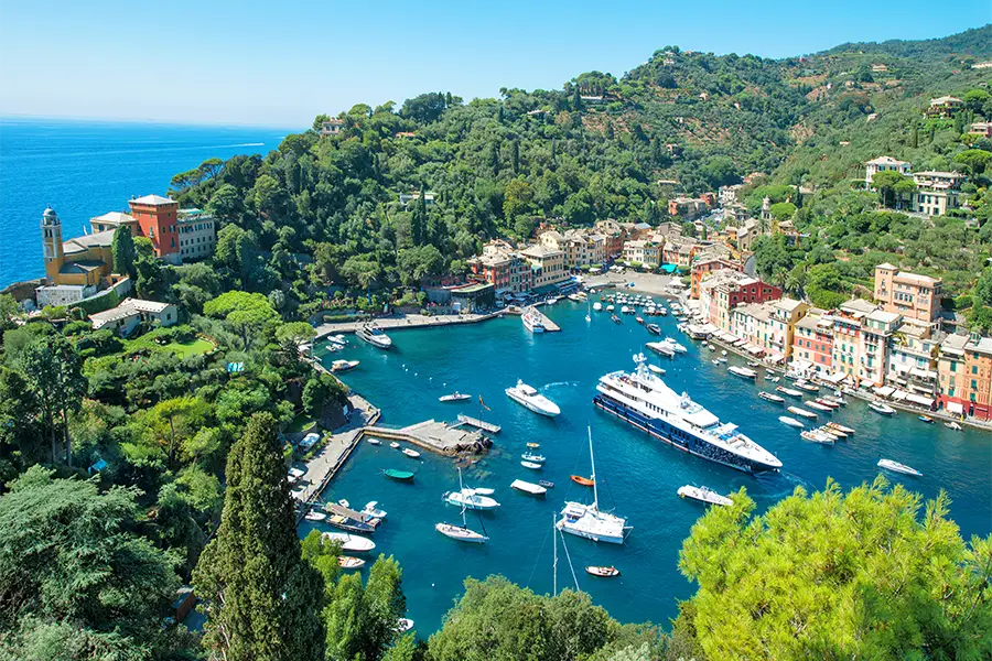 Panoramic view of Portofino, in Liguria, with yachts and boats anchored in the harbor — one of the most charming destinations for boat tours in Italy