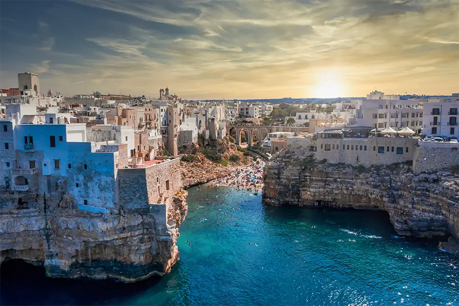 Aerial view of Polignano a Mare with cliffs, blue sea, and hidden beach — ideal for boat tours in Italy exploring caves and secret coves