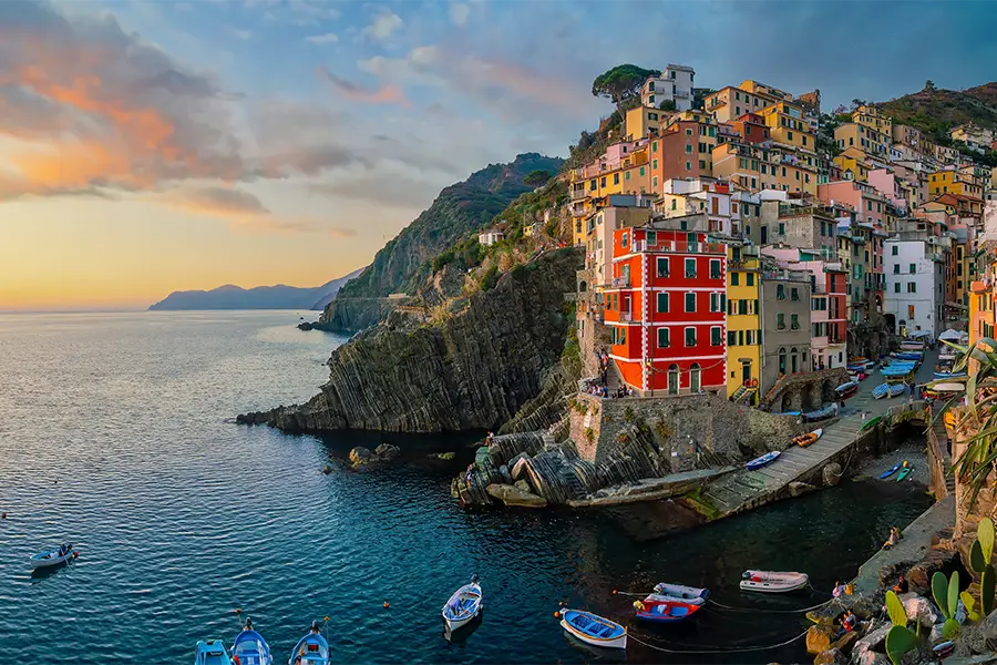 Boats anchored next to the colorful houses of Riomaggiore at sunset, a classic setting for boat tours in Italy through the Cinque Terre region