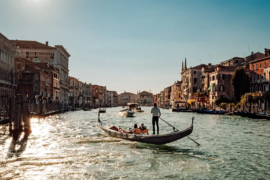 Gôndola navegando pelo Grande Canal em Veneza ao entardecer, um dos passeios de barco na Itália mais icônicos e românticos.
