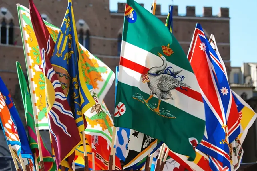 Colorful flags representing Siena’s different contrade, proudly displayed during the Palio di Siena.