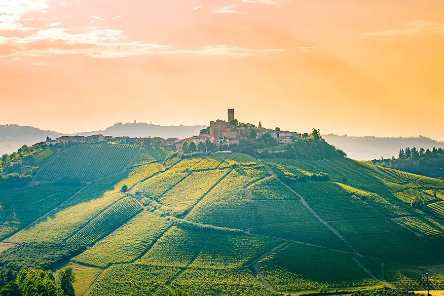 Hilltop village of Barolo in Piedmont surrounded by rolling vineyards at sunset