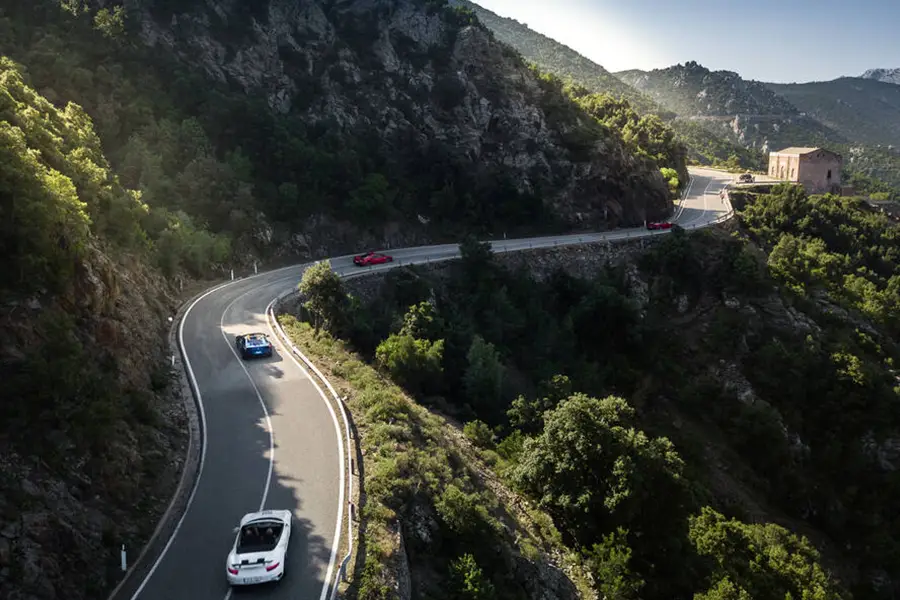 Winding mountain road SS125 Orientale Sarda in Sardinia with cars driving through rocky cliffs and green forests